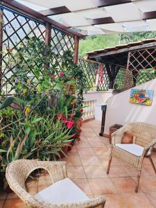 eine Terrasse mit Korbstühlen, Tischen und Pflanzen in der Unterkunft Appartamenti via Lombardo in Giardini-Naxos