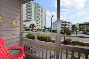 a red chair on a balcony with a view of a street at Sweet Caroline Remodeled with Partial Ocean View and Oceanfront Pool in Myrtle Beach
