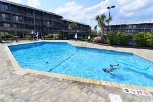 a swimming pool with people in the water at Sweet Caroline Remodeled with Partial Ocean View and Oceanfront Pool in Myrtle Beach