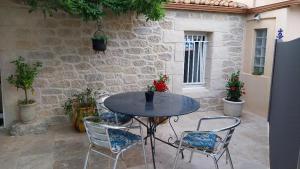 einen Tisch und Stühle vor einer Steinmauer in der Unterkunft Le mazet en été - studio en garrigue nimoise in Nîmes