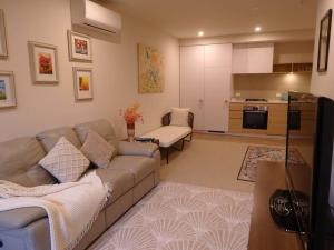 Caulfield Village Apartment في ملبورن: غرفة معيشة مع أريكة ومطبخ