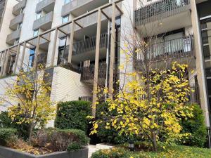 a building with trees and flowers in front of it at Caulfield Village Apartment in Melbourne