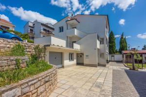 a large white house with a stone wall at Apartments Luna in Dramalj
