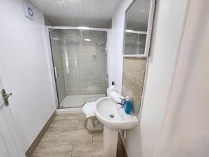 a white bathroom with a sink and a shower at Solihull Shared House in Birmingham