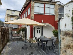 einen Tisch und Stühle mit einem Regenschirm vor einem Gebäude in der Unterkunft Casa Manuel in Toldaos