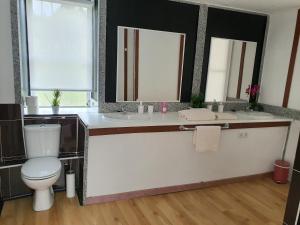 ein Badezimmer mit zwei Waschbecken und einer Toilette und zwei Spiegeln in der Unterkunft Casa Manuel in Toldaos + 7 Fotos