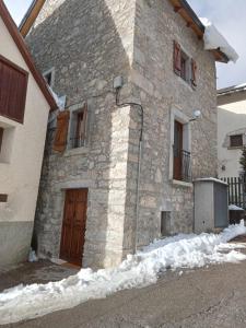 a stone building with a wooden door in the snow at Casitas centro panticosa in Panticosa