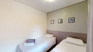 2 Betten in einem Zimmer mit weißen Wänden in der Unterkunft Studio 6 Pinheiros by Oba in São Paulo