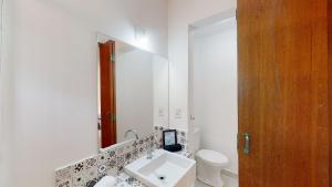 ein weißes Badezimmer mit einem Waschbecken und einem Spiegel in der Unterkunft Studio 6 Pinheiros by Oba in São Paulo