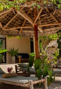 a straw umbrella and chairs in a resort at The Garden in Paje