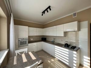 a kitchen with white cabinets and a table in it at Apartament Wojska Polskiego 45 in Wadowice