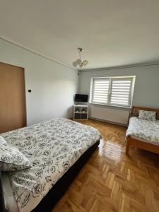 a bedroom with a bed and a table and two windows at Apartament Wojska Polskiego 45 in Wadowice