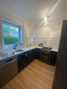 cocina con armarios azules, fregadero y ventana en St Andrews Holiday Home en Fife