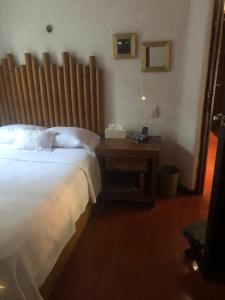 Schlafzimmer mit einem Bett mit einem Kopfteil aus Holz in der Unterkunft Casablanca in Cancún