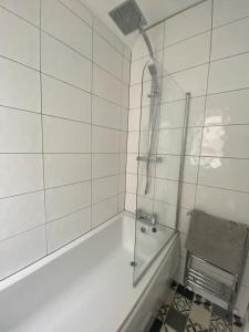 y baño blanco con ducha y bañera. en St Andrews Holiday Home en Fife