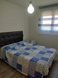a bedroom with a blue and white quilt on a bed at WANDA Patrimonio parking gratis LICENCIA TURISTICA VT-13975 in Alcalá de Henares