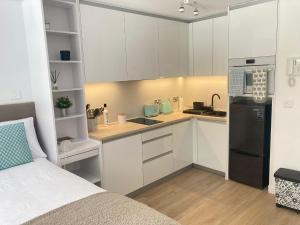 a kitchen with white cabinets and a black refrigerator at CP luxury studio in Gibraltar