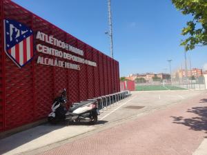 una moto está estacionada junto a una pared roja en WANDA Patrimonio parking gratis LICENCIA TURISTICA VT-13975, en Alcalá de Henares