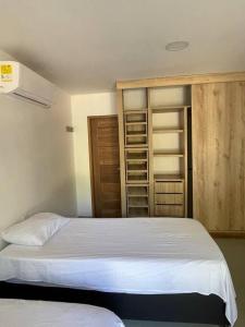 ein Schlafzimmer mit einem weißen Bett und einem Schrank in der Unterkunft Hermoso apartamento en el corazon del carnaval in Barranquilla