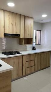 una cocina con armarios de madera y encimeras blancas en Hermoso apartamento en el corazon del carnaval, en Barranquilla