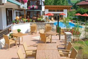 a patio with tables and chairs next to a pool at Gästehaus Weißes Rössl in Reit im Winkl