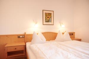ein Bett mit weißer Bettwäsche und zwei Leuchten drauf in der Unterkunft Haus Lofertal in Reit im Winkl