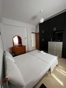 a white bed in a room with black cabinets at Vila Eriseld in Ksamil