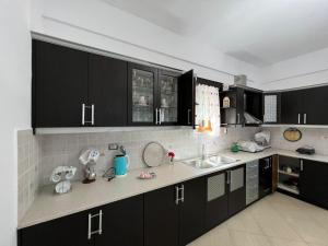 a kitchen with black cabinets and white counter tops at Vila Eriseld in Ksamil