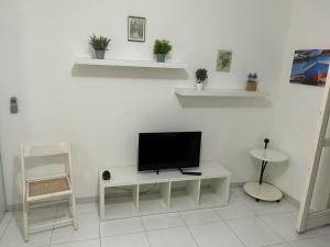 - un salon avec une télévision sur un mur blanc dans l'établissement Portorosa, à Torre Forte