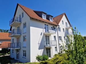 ein weißes Apartmenthaus mit Balkonen und Bäumen in der Unterkunft Hotel Siebeneichen  in Meißen