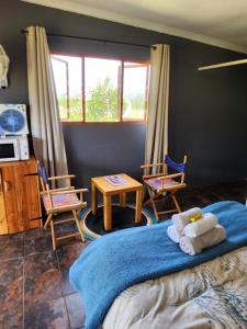 Schlafzimmer mit einem Bett mit 2 Stühlen und einem Tisch in der Unterkunft Mulberry Country Cottage in Brits