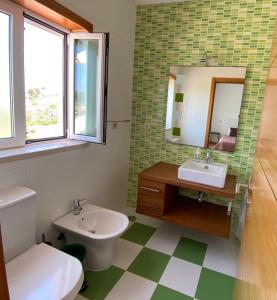 een badkamer met een wastafel, een toilet en een spiegel bij Alice's House in Nazaré