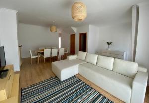 a living room with a white couch and a table at Alice's House in Nazaré