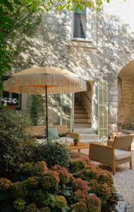 patio con sedie e ombrellone di fronte a un edificio di L'Abbaye Hôtel a La Colle-sur-Loup