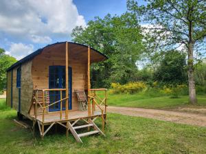 a small wooden cabin with two chairs in the grass at L'alternatif in Huriel +91 photos