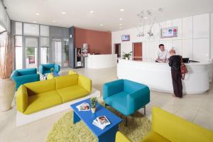 a man and a woman standing at a counter in a lobby at Apartments Polynesia Plava Laguna in Umag