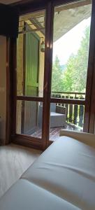 una camera da letto con una grande finestra con vista su un balcone di Casa Natura a Castione della Presolana