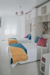 a white bedroom with two beds with colorful pillows at Meu Lar in Rianjo