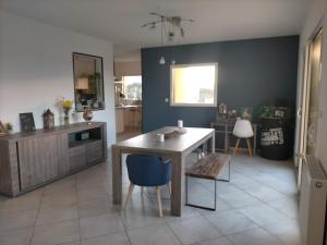 a kitchen with a wooden table and a blue wall at Maison du phare. in Plouarzel