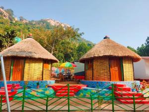 un groupe de cabanes avec des chaises et des parasols dans l'établissement Chamtaburu Eco Resort, à Bāghmundi