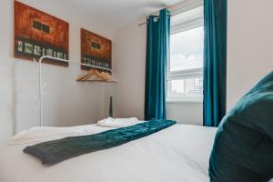 a bedroom with a bed with blue curtains and a window at Stylish 2 Bed Manchester Flat in Manchester