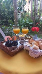 a table with baskets of food and glasses of orange juice at Villa dos Pássaros Paraty Hospedagem in Paraty