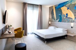 セニガッリアにあるHotel Cristalloのベッド、デスク、椅子が備わるホテルルームです。