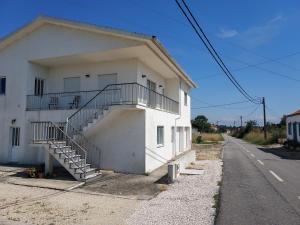 a white building with a staircase next to a street at Casa Férias in Seixo de Gatões