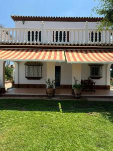 una casa con toldo a rayas y un patio verde en VILLA LA MOMITA, en Chiclana de la Frontera
