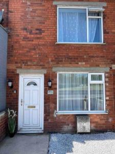 - un bâtiment en briques avec une porte blanche et une fenêtre dans l'établissement Modern and spacious house with Hot Tub, à Lincolnshire