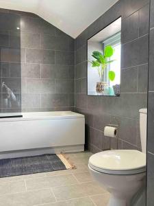 a bathroom with a toilet and a tub and a window at Modern and spacious house with Hot Tub in Lincolnshire