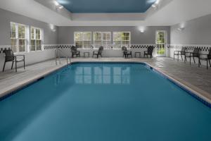 a pool with chairs and tables in a room with at Residence Inn Long Island Holtsville in Holtsville
