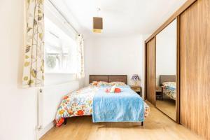 1 dormitorio con cama y espejo grande en Spacious 3BHK near Heathrow en Cranford