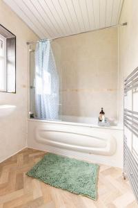 ein Badezimmer mit einer Badewanne und einem grünen Teppich in der Unterkunft Spacious 3BHK near Heathrow in Cranford